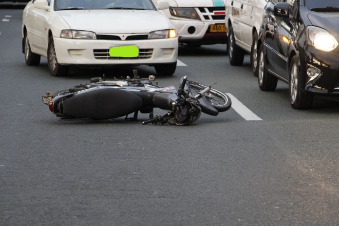 Motocicleta caída em via urbana com carros ao redor, representando os acidentes de trânsito em Manaus